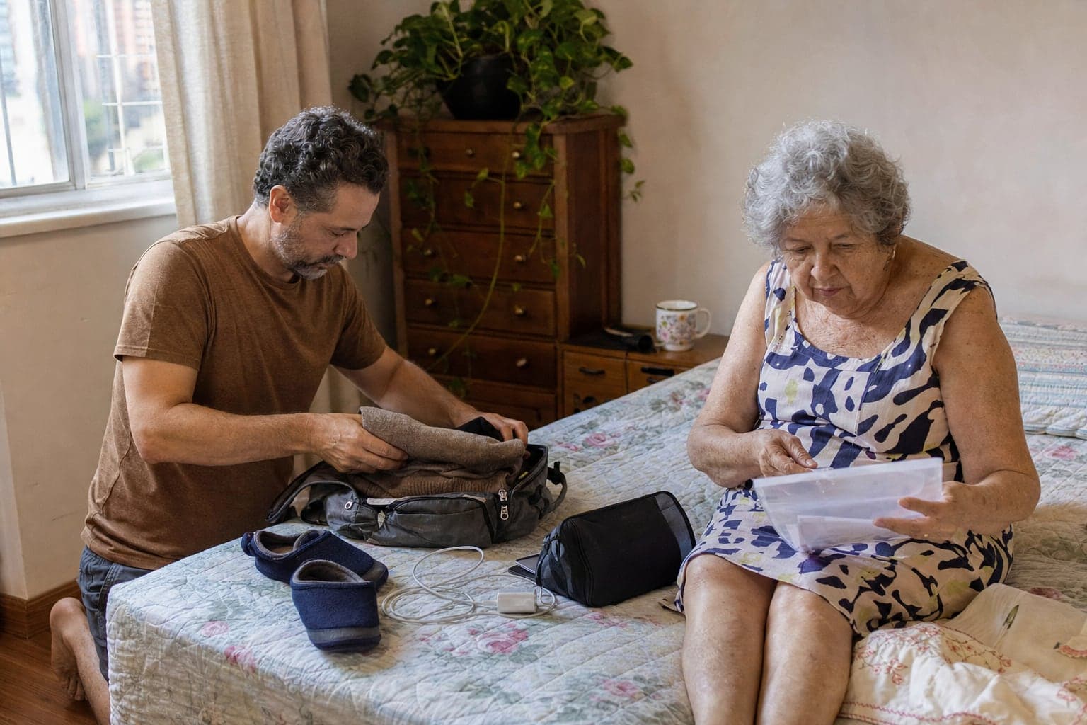 Filho arruma uma bolsa sobre a cama enquanto a mãe idosa confere papéis numa pasta plástica